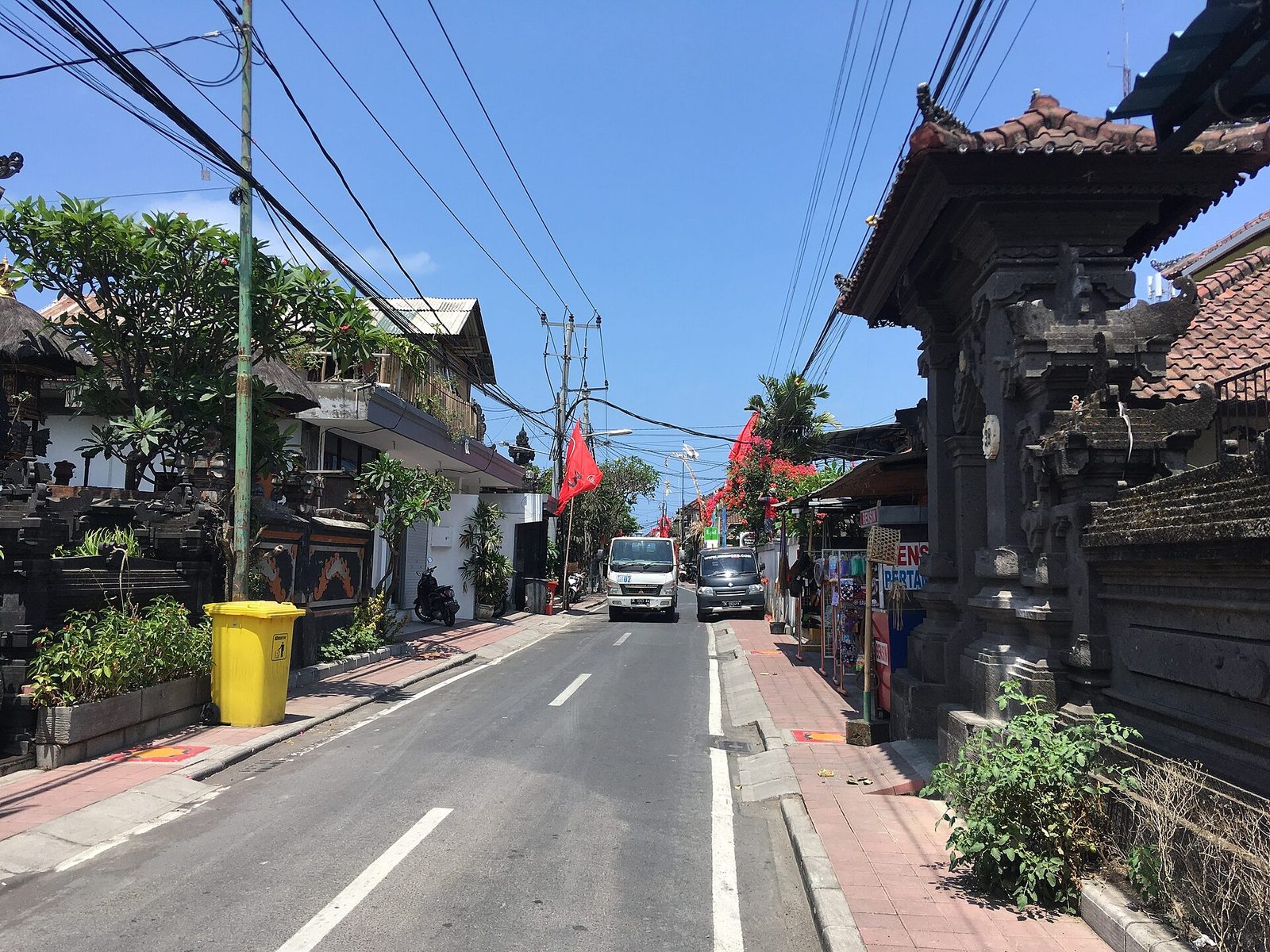 Narrow street with a temple gate and parked scooters in Seminyak