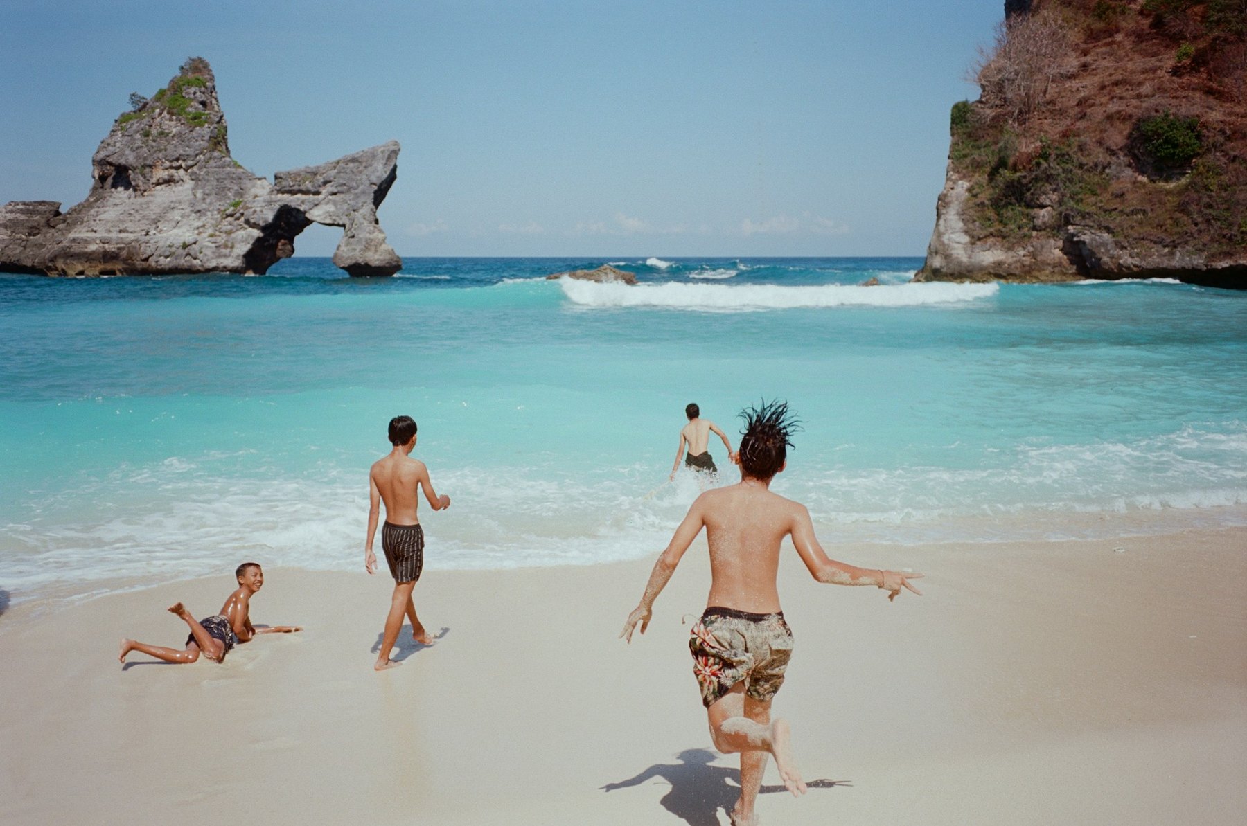 Visitors on Atuh Beach with offshore rocks beyond the sand