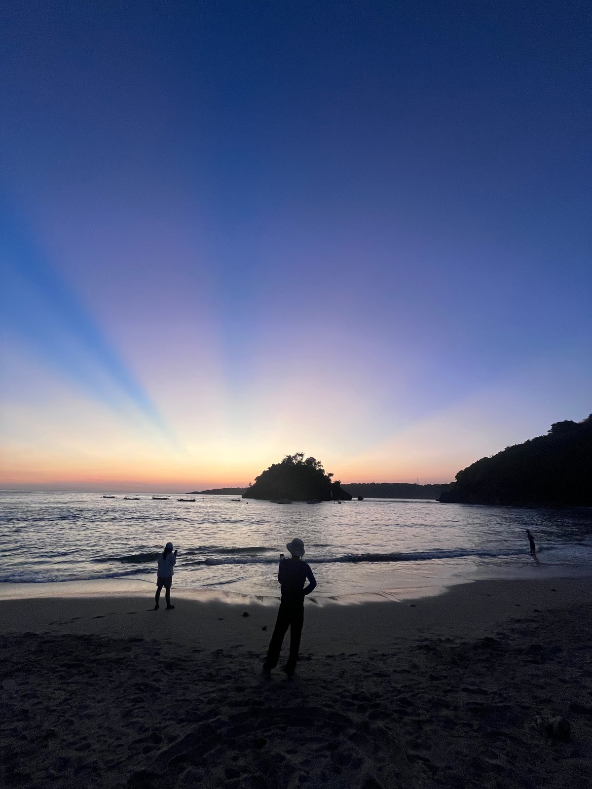 人们站在 Crystal Bay 海滩上，远处的岛屿在轮廓中。