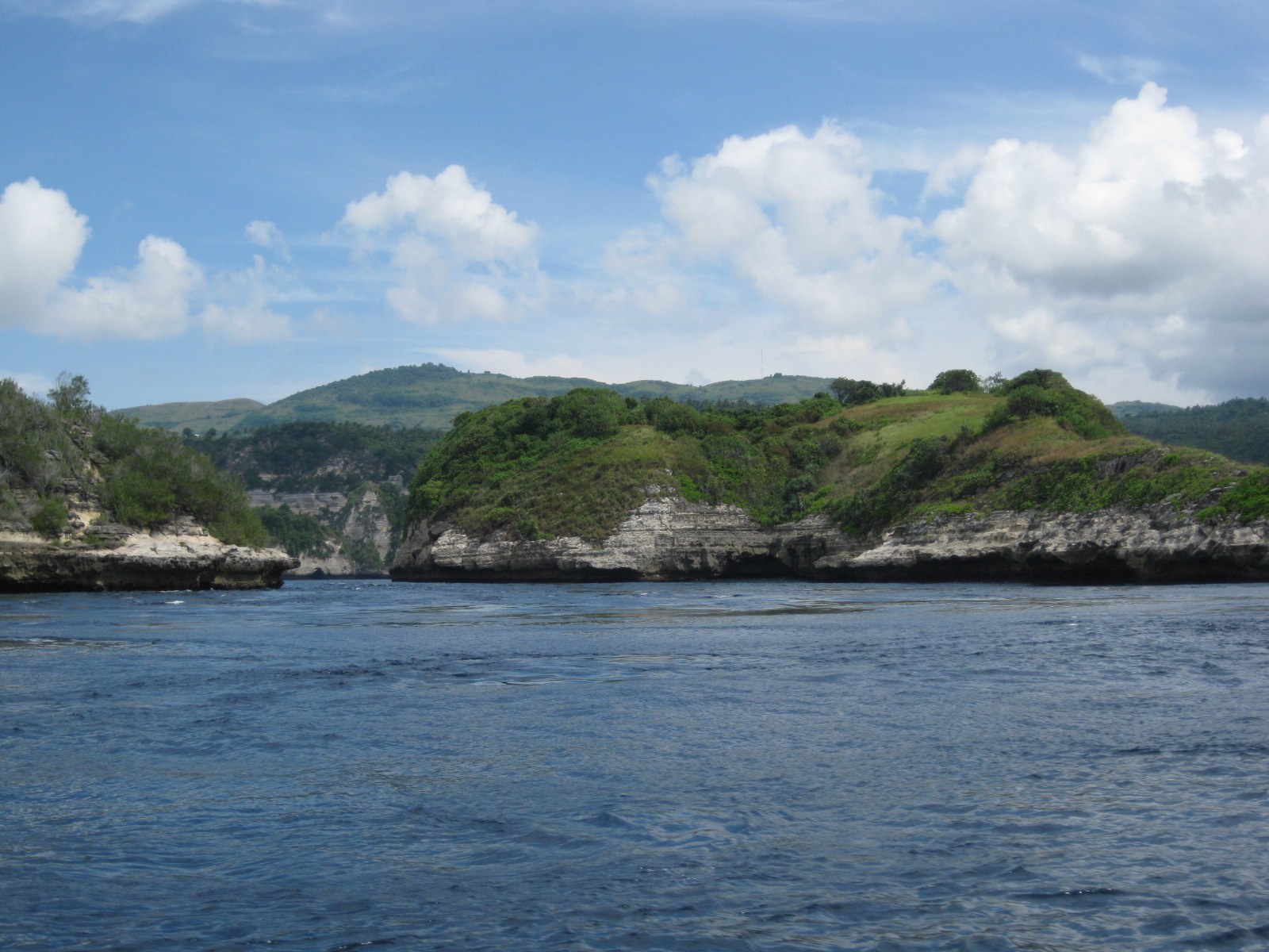 Green hills and limestone coast viewed from the sea at Nusa Penida