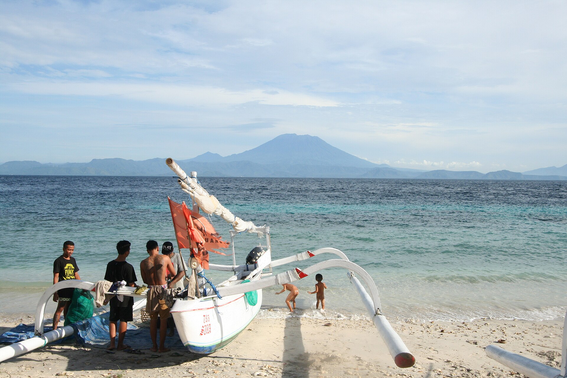 Local boat on a Nusa Penida beach with Bali visible across the strait