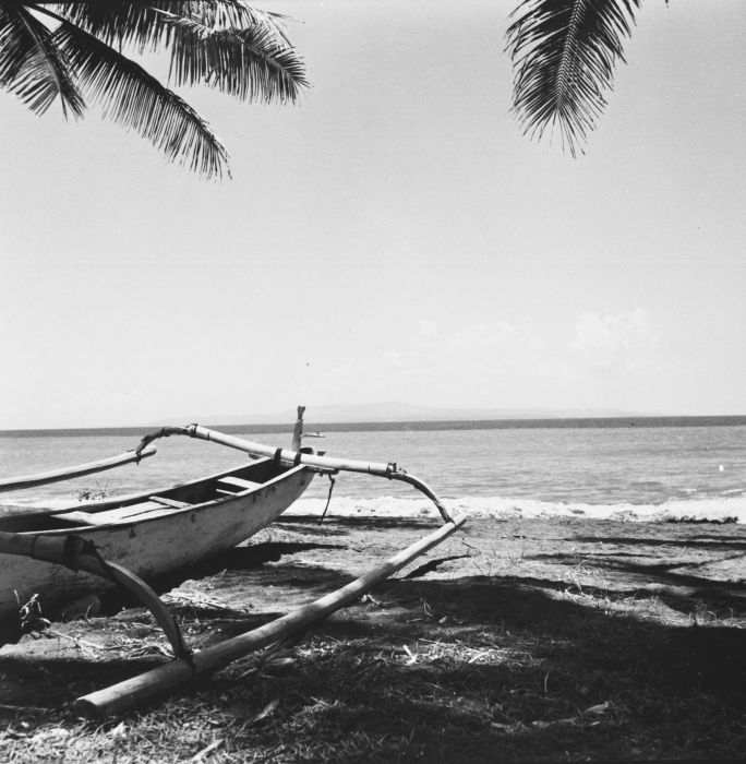 Historic view of Nusa Penida across the sea with a traditional boat on the beach