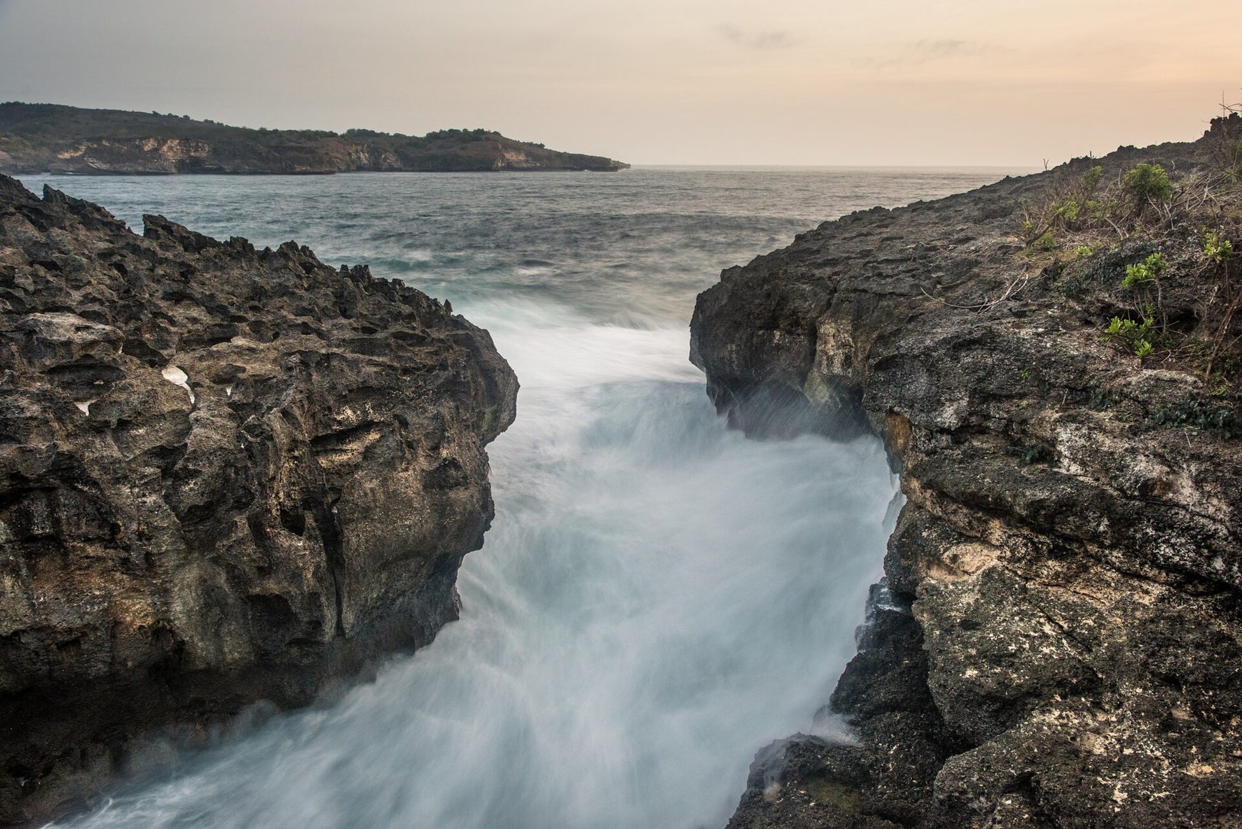 White water from a wave pouring through Angel's Billabong's rock channel at dusk.