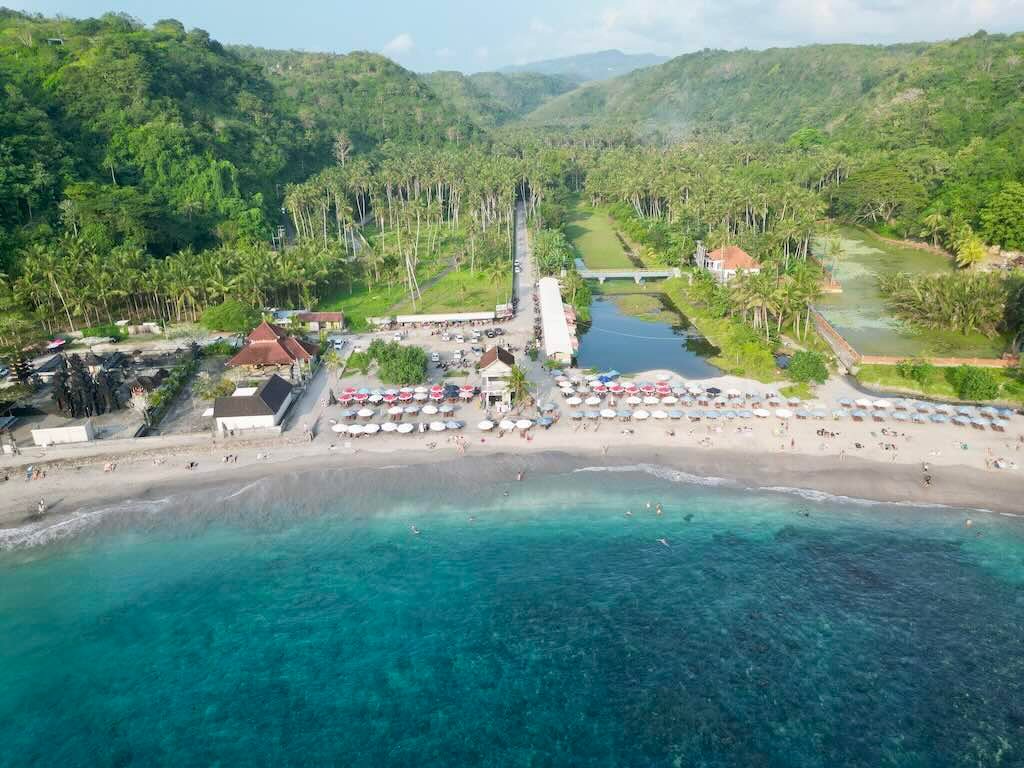 Aerial view of Crystal Bay beach, palm grove, parking area, and surrounding hills