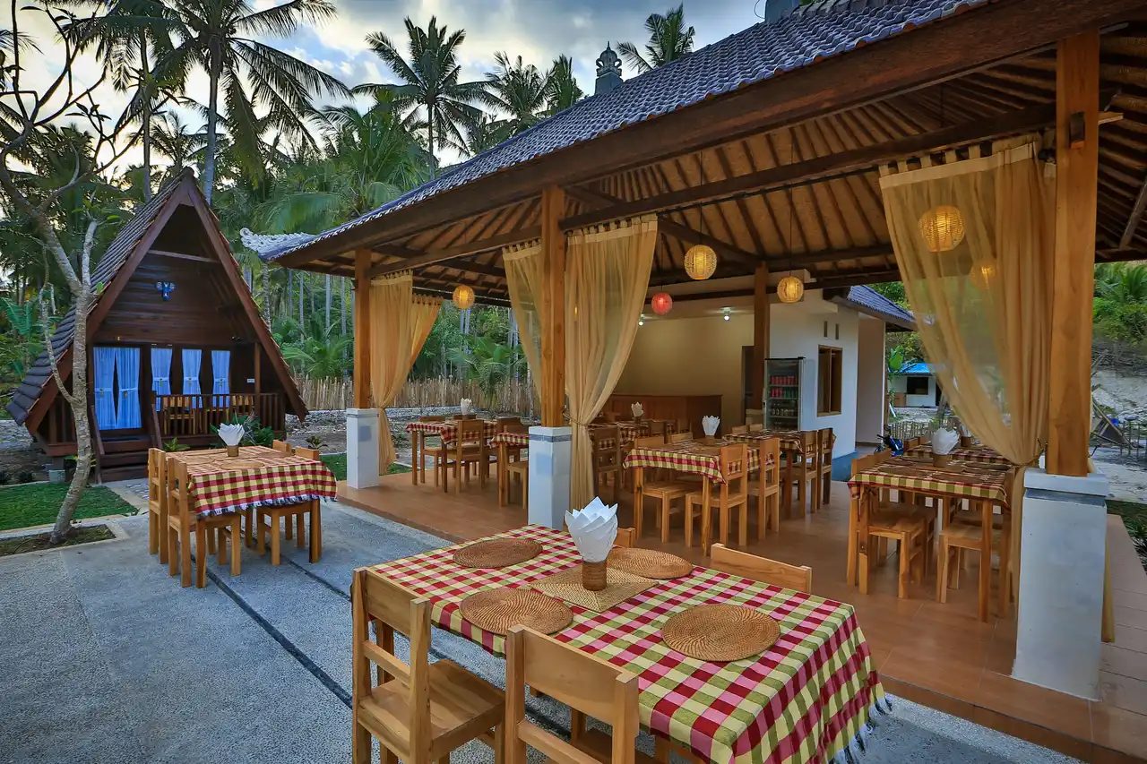 Open-air pavilion at Kavana Penida with checked tablecloths, curtains and a garden of palms